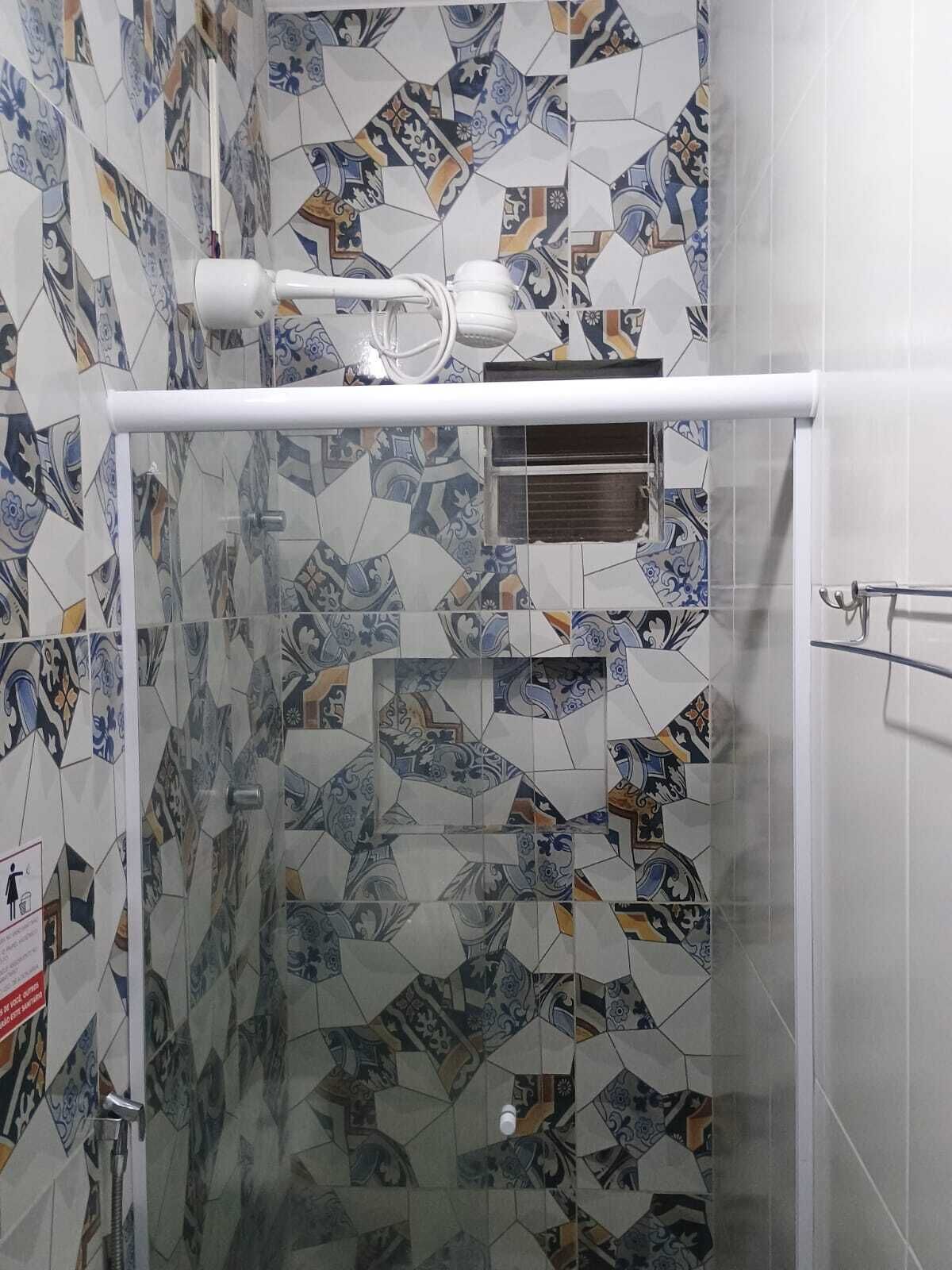 Ducha con puerta de cristal, toallero blanco y cabezal de ducha.