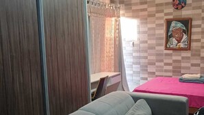 Una sala de estar con un sofá, una mesa con mantel rosa y una pared con estampado de cuadros.
