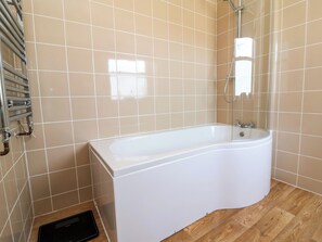 Ein Badezimmer mit einer weißen Badewanne, einer Duschbrause und einem Handtuchhalter.