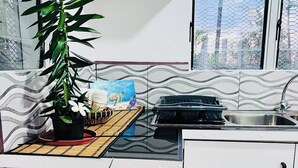 Una cucina moderna con mobili bianchi, un piano cottura a gas, un lavello e una finestra con vista sugli edifici.