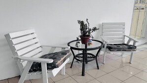Due sedie bianche, un tavolino rotondo con una pianta in vaso e un pavimento piastrellato.