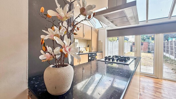 A modern kitchen with a central island, a potted plant, and a view of the backyard through large sliding doors. - Modern 3BDR Family House in North Stifford (North Stifford)