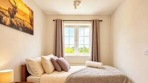 A bedroom with a bed, a nightstand, a lamp, and a window with curtains. - Modern 3BDR Family House in North Stifford (North Stifford)