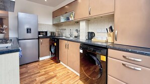 A modern kitchen with stainless steel appliances, wooden flooring, and a dishwasher. - Modern 3BDR Family House in North Stifford (North Stifford)