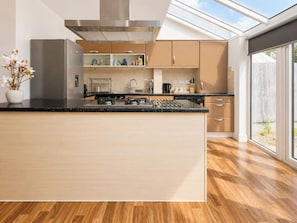 A modern kitchen with a large island, stainless steel appliances, and a view through the glass door. - Modern 3BDR Family House in North Stifford (North Stifford)