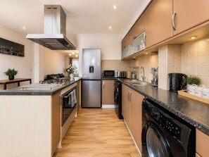 Una cocina moderna con un refrigerador de acero inoxidable, microondas, lavavajillas y cafetera.