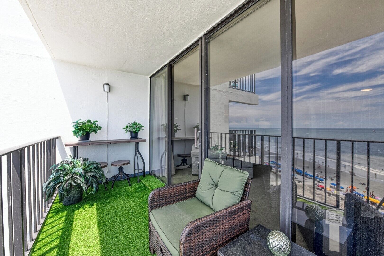A balcony with a wicker chair, a small table, and potted plants.