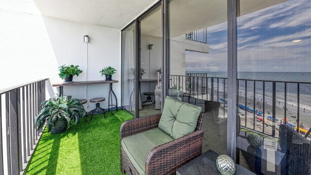 Un balcon avec un fauteuil en osier, une petite table et des plantes en pot.