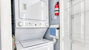 Un espace buanderie compact comprenant un lave-linge, un sèche-linge et un chauffe-eau.