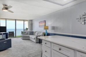 A modern living room with a sofa, TV, and a balcony with a view. - Royal Garden Resort 802 - One Bedroom, Two Bath Oceanfront Condo (Garden City Beach)