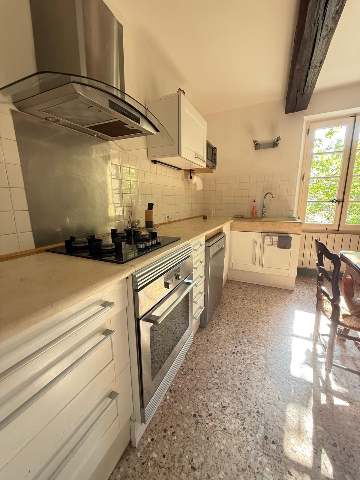 A kitchen with white cabinetry, a stainless steel range hood, a built-in oven, and a granite countertop.