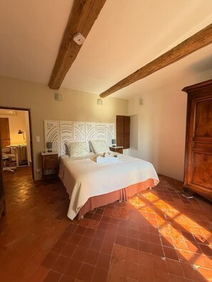 Une chambre à coucher avec un lit, des poutres en bois, une armoire et une table de chevet.