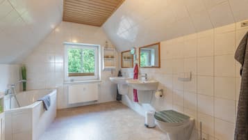 Un baño con bañera, lavamanos, inodoro y ventana.