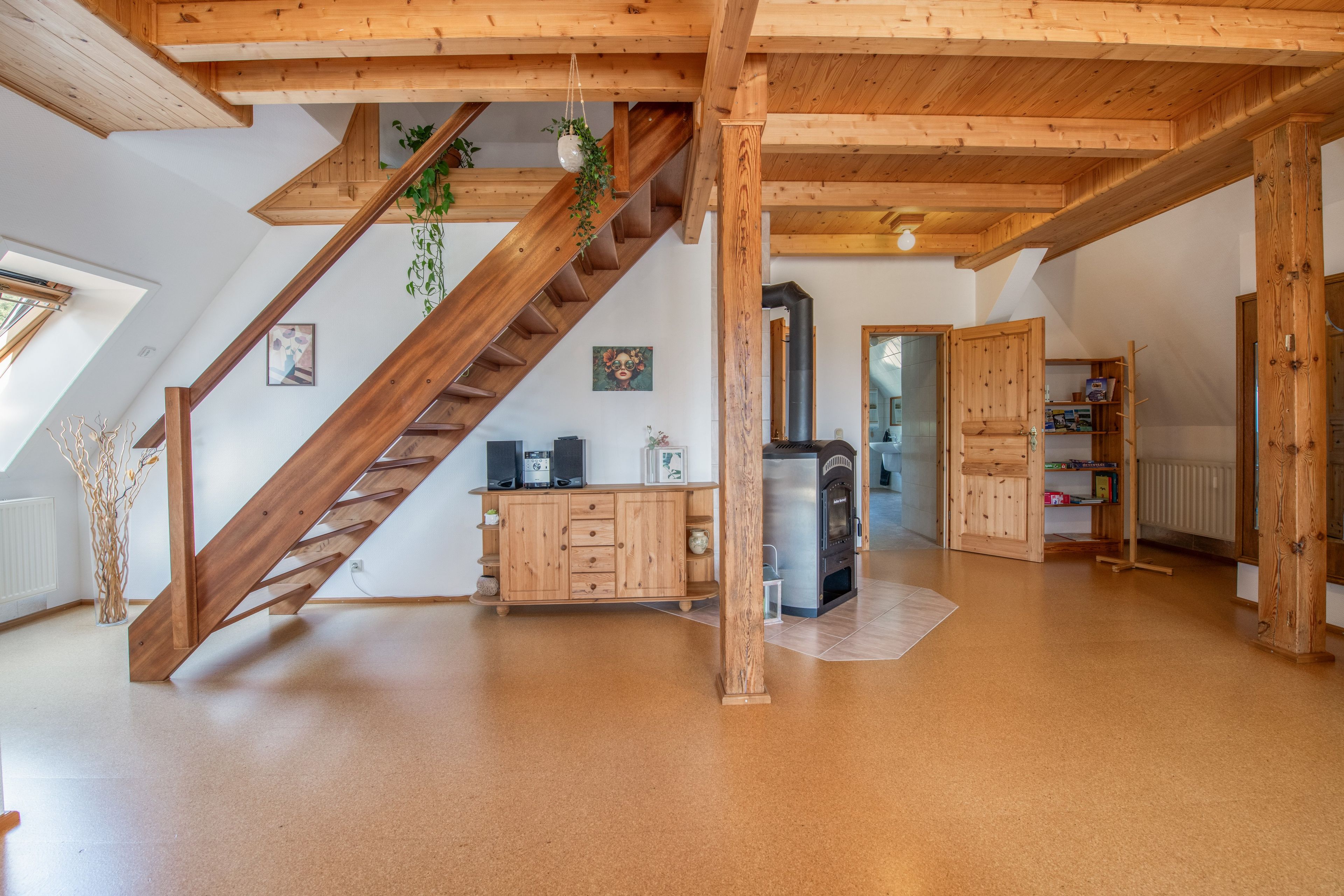 A spacious loft with a wooden staircase, a built-in fireplace, and a view of the outdoors.