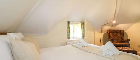 A bedroom with a large bed, a chair, and a window with curtains.