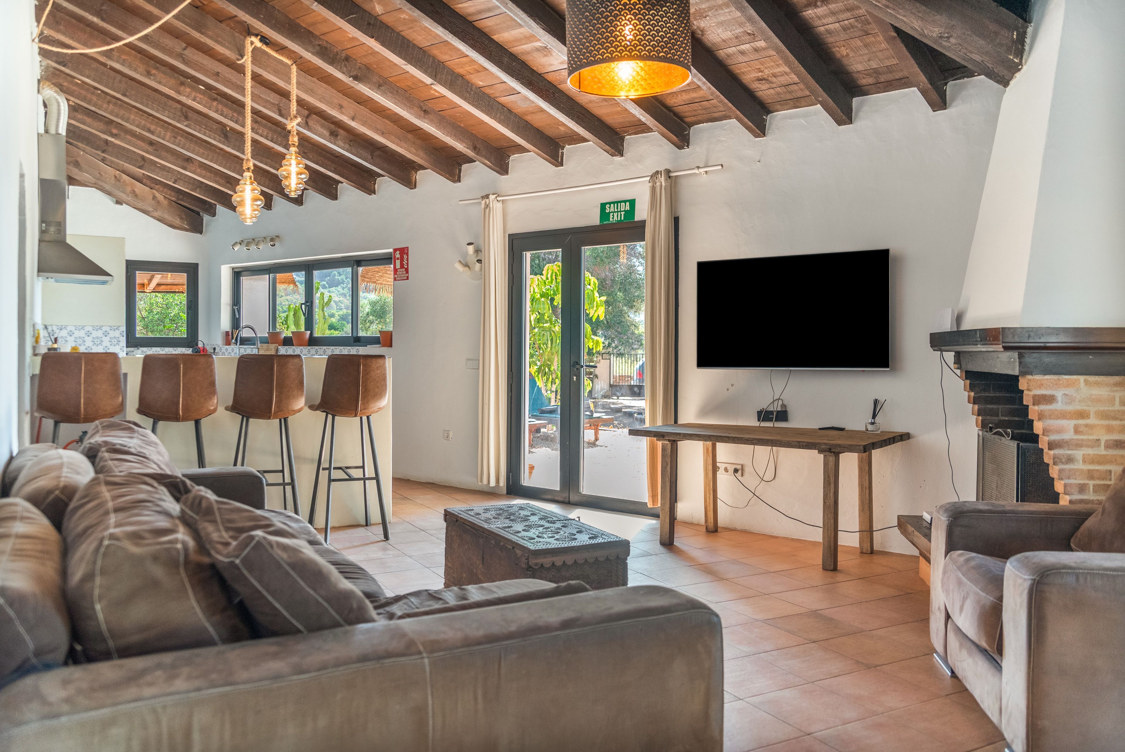 Un intérieur moderne avec un canapé, des tabourets de bar, un téléviseur et une cheminée.