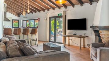 Un intérieur moderne avec un canapé, des tabourets de bar, un téléviseur et une cheminée.