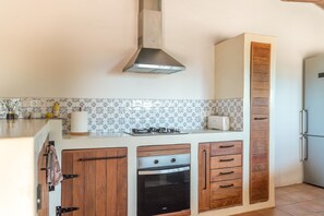 Una cocina con estufa, horno y un armario alto.