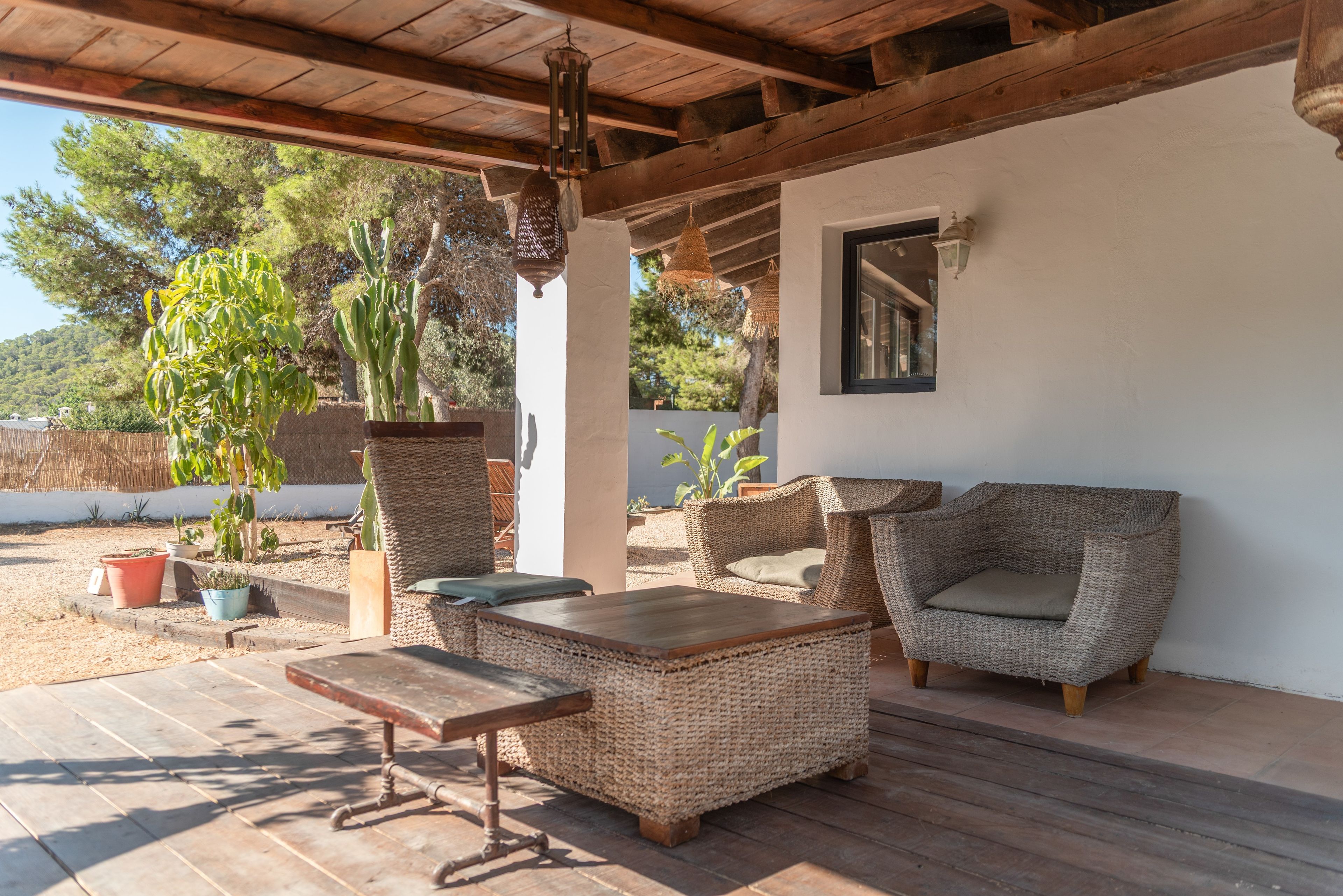 Une terrasse extérieure aménagée avec des meubles en osier, une table en bois et des plantes en pot.