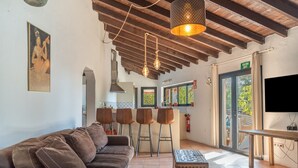 Ein modernes Interieur mit einer Couch, Barhocker, einem Fernseher und einer Küchenzeile.