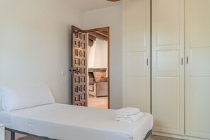 Un dormitorio con cama, armario y puerta que da a un baño.