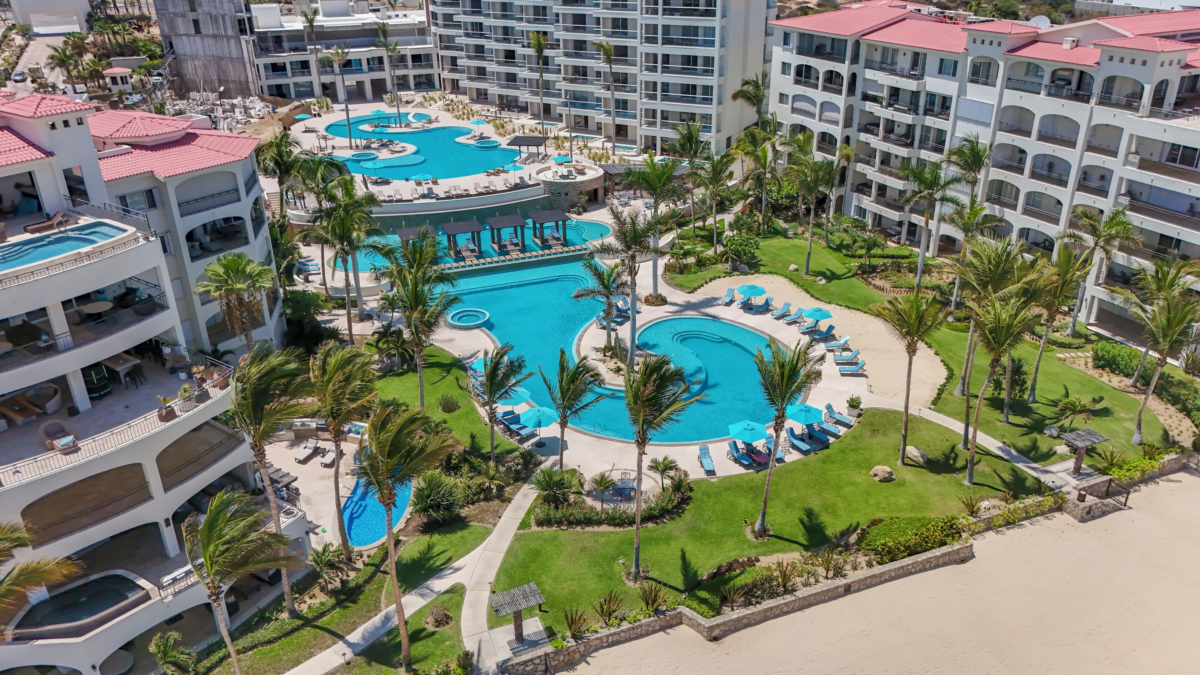 Un resort con diverse piscine, palme e spiaggia.
