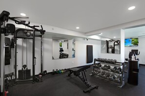 A modern gym with various exercise equipment, including a squat rack, bench press, and dumbbells. - 🏖️Gulf Views | Steps to Beach | Beachfront Complex | Island Winds 1003 🏖️ (Fort Myers Beach)