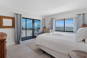 Ein Hotelzimmer mit einem großen Bett, Meerblick und einem Balkon mit Geländer.