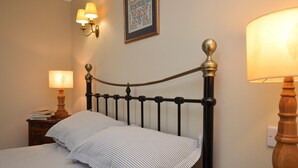 A neatly made bed with striped bedding, a bedside lamp, and a wall-mounted light fixture. - Cuil Steading -  Spectacular Loch Views & Garden (Cairndow)