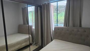 Ein Zimmer mit zwei Betten, einem Schlafsofa und einem Fenster mit Vorhängen.