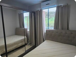 A room with two beds, a sofa, and a window with curtains.