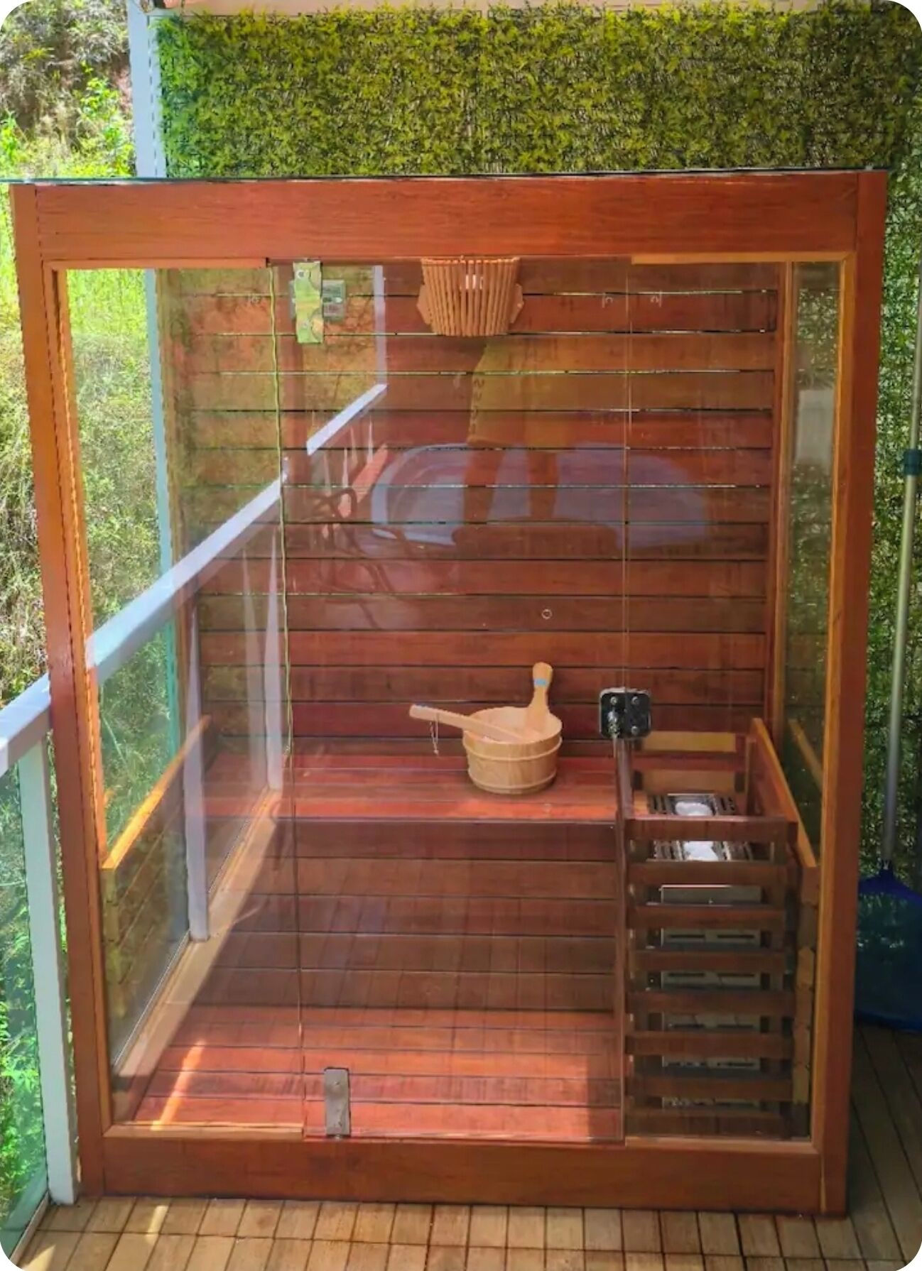 A sauna with a wooden interior, a wooden bench, a wooden bucket, and a metal rack.