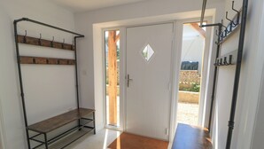 A room with a door, a bench, and a metal rack with hooks. - Cern-wyn (Chippenham)
