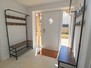 A room with a door, a bench, and a metal rack with hooks.