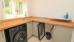A compact kitchen with a washing machine, a sink, and a drying rack. - Cern-wyn (Chippenham)