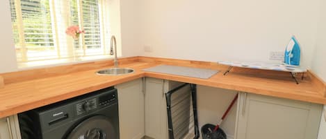 A compact kitchen with a washing machine, a sink, and a drying rack.