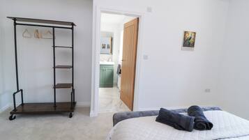 A bedroom with a bed, a wardrobe, and a hallway leading to a bathroom.