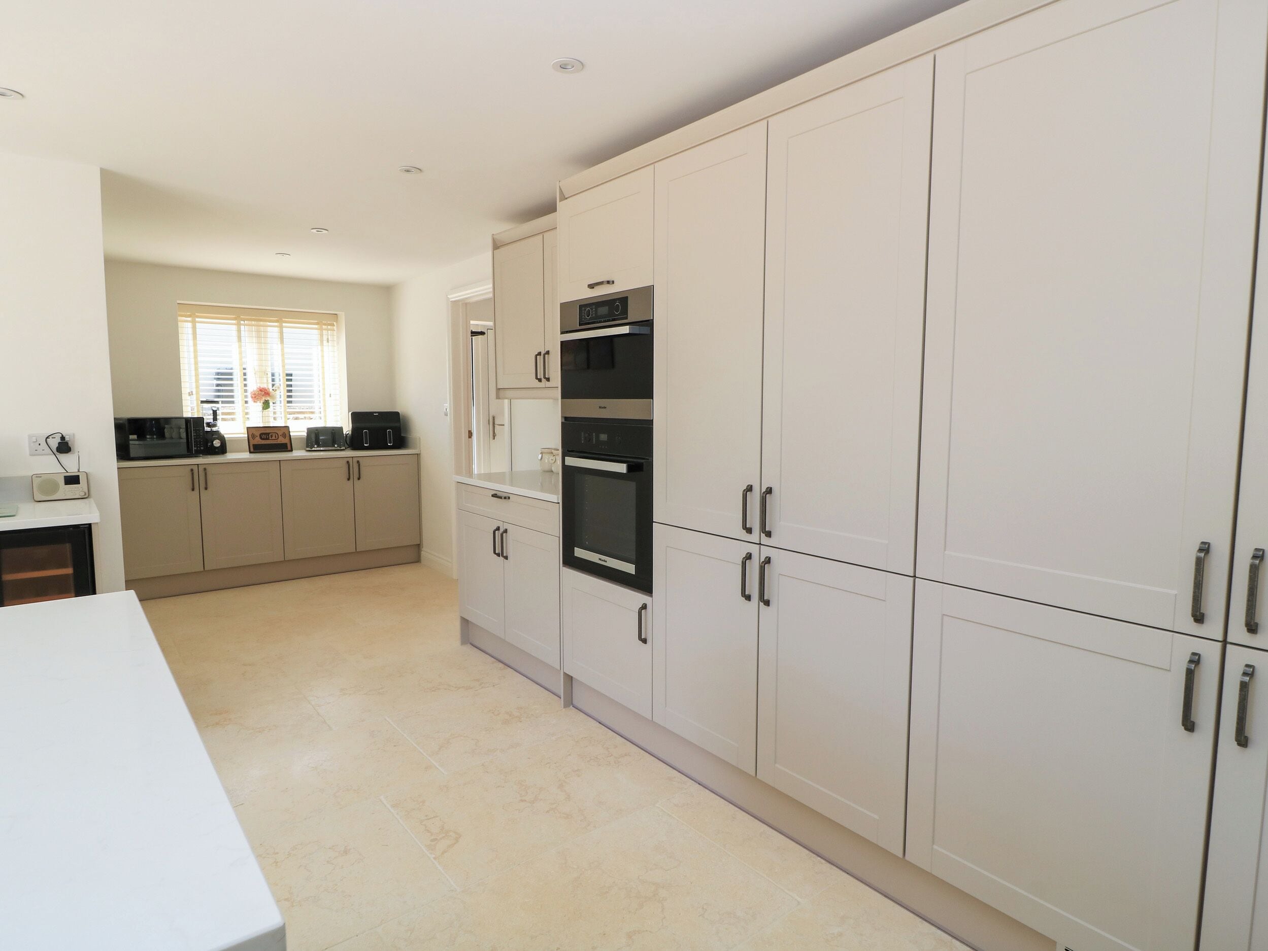 A modern kitchen with white cabinets, a microwave, and an oven.