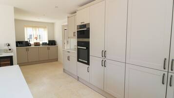 A modern kitchen with white cabinets, a microwave, and an oven.
