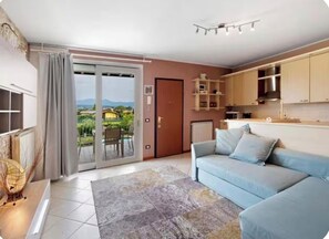A modern living room with a sofa, a coffee table, and a view through a sliding glass door to an outdoor area. - Casa delle Rondini - Pool, Relaxation, and Lake Garda (MANERBA DEL GARDA)