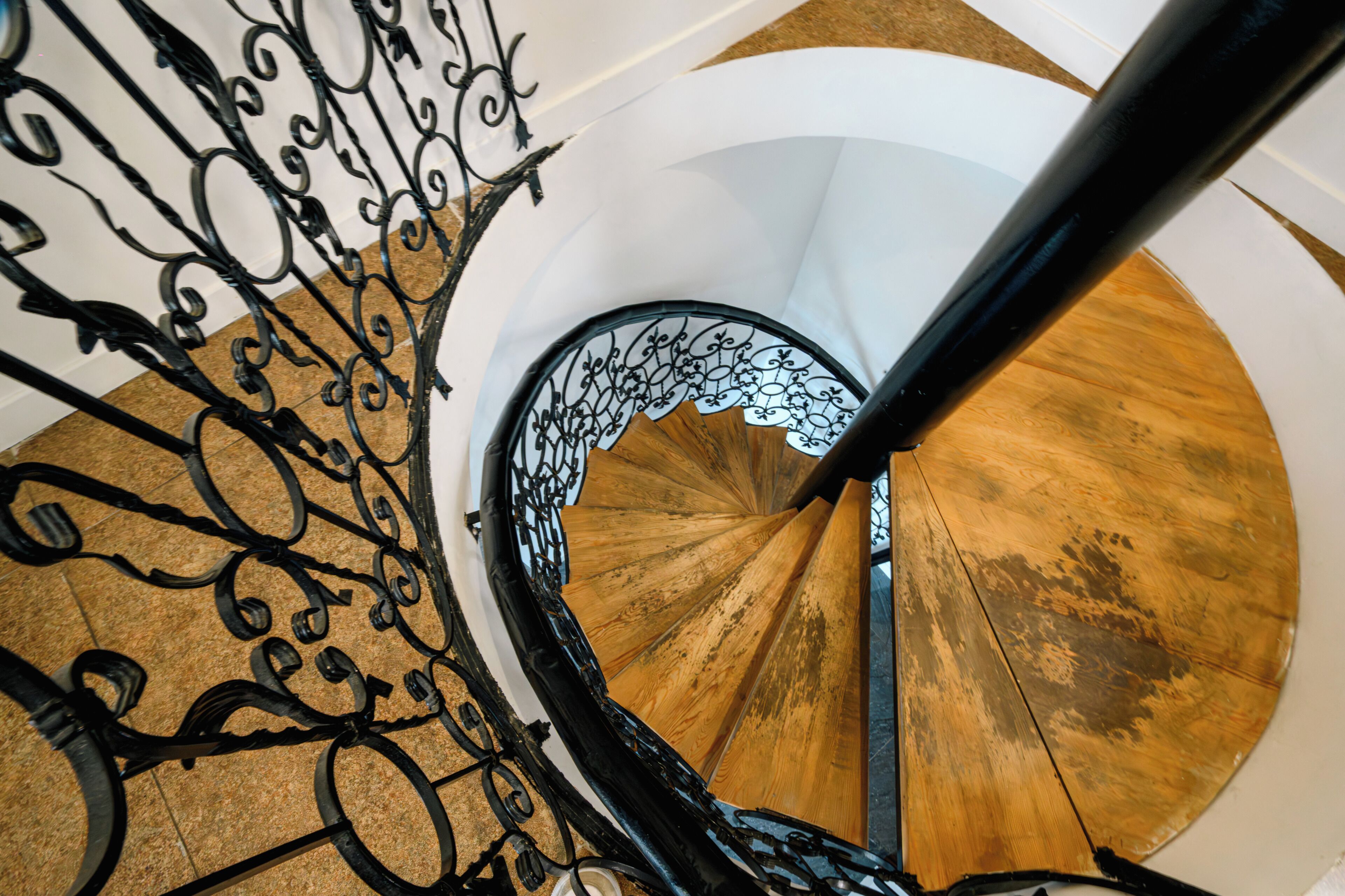 Un escalier en colimaçon avec des rampes en métal ouvragé et des marches en bois.