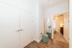 A hallway with white doors, a mirror, and a green ottoman. - Brand-New Spacious Flat | For Business & Leisure - Pass the Keys (Reading)