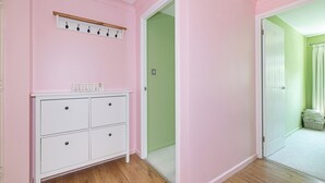 A room with pink walls, a white dresser, a wooden coat rack, and a green door. - Bright, Leafy Oasis in South London - Pass the Keys (London)