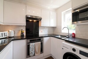 Eine kleine Küche mit Backofen, Mikrowelle, Spüle und Waschmaschine.