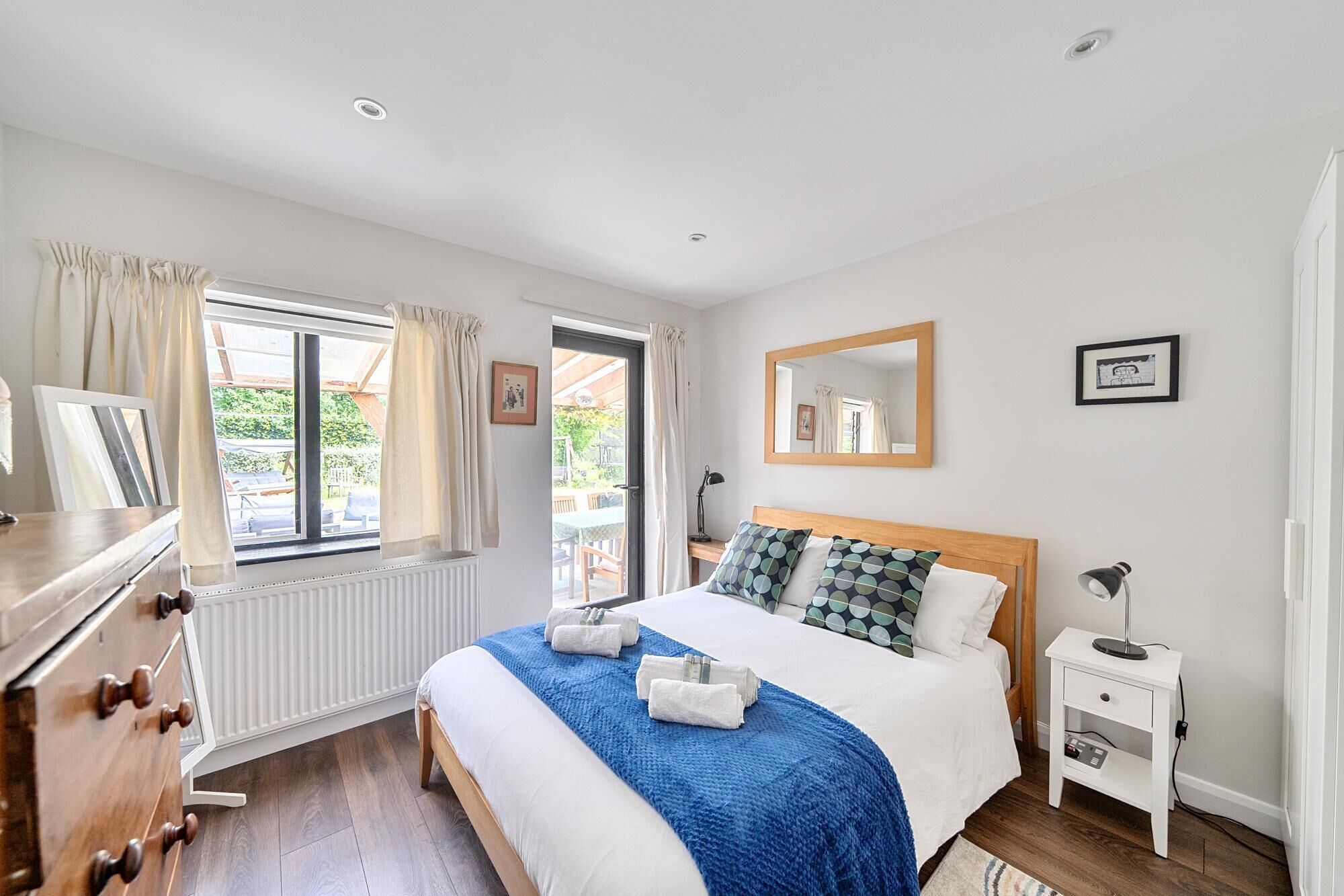 A bedroom with a bed, bedside table, lamp, and a window with curtains.