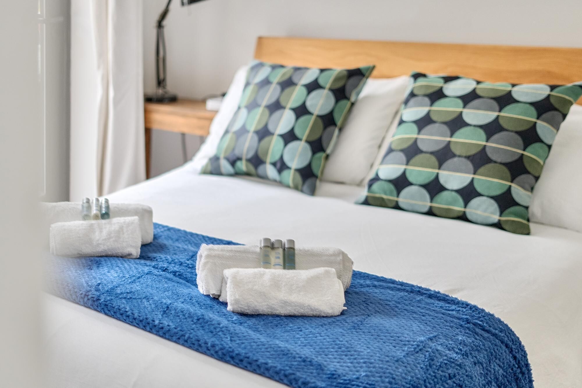 A neatly made bed with a blue towel and toiletries on a white bedspread.