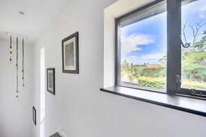Ein Zimmer mit großem Fenster, einer Deckenleuchte und gerahmten Bildern an der Wand.