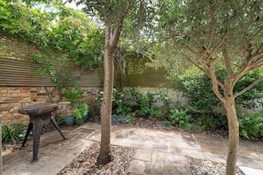 A patio with stone flooring, a metal grill, and a tree. - Stylish Stockwell House with Garden & Comfort  - Pass the Keys (London)