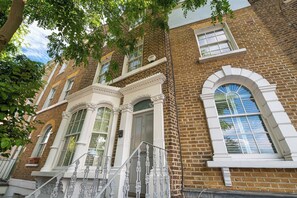 A brick building with white trim, large windows, and a staircase. - Stylish Stockwell House with Garden & Comfort  - Pass the Keys (London)