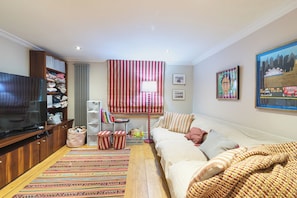 A living room with a television, sofa, and a large window with curtains. - Stylish Stockwell House with Garden & Comfort  - Pass the Keys (London)